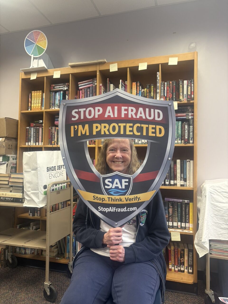 A senior participant proudly holds the StopAiFraud awareness shield after completing an AI fraud prevention workshop.